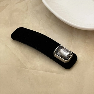 Detail of a vintage black velvet hair clip with a rectangle grey gemstone and silver frame