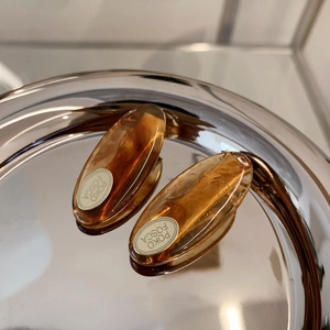 Macro detail of amber acetate hair clip featuring a polished silver logo plate inlay