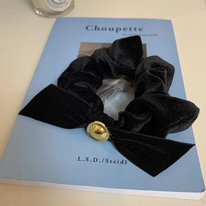 Detail showing high-quality black velvet scrunchie with bow and gold metal buckle