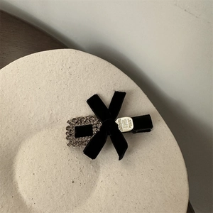 Vue macro d'une barrette en velours noir avec boucle en strass et étiquette en métal