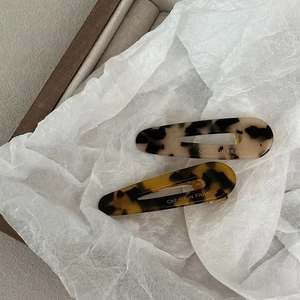 Detail view of acetate tortoise shell hair clips with golden Creation France lettering