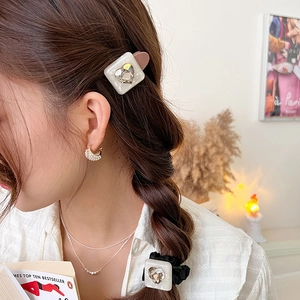 Close-up of leopard heart scrunchie and hair clip set with elegant pearls and gold jewelry