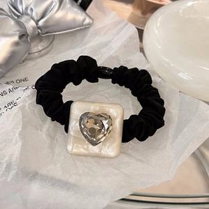 Close-up of leopard heart crystal on pleated black scrunchie with marble resin base