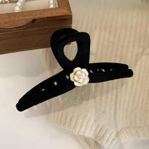 Detail of a large black flocked hair claw with a white camellia flower and pearl accent