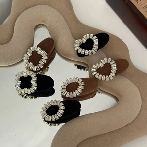 Detail view of vintage rhinestone hair clips with heart and round patterns on velvet base