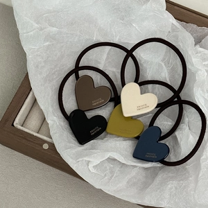 Dettaglio di ciondoli a cuore su elastici per capelli in cinque colori su legno