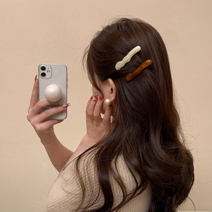 Gros plan de barrettes irrégulières en acrylique blanc crème et ambre sur modèle