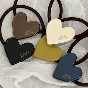 Dettaglio di elastici per capelli con ciondoli a cuore in acetato in cinque colori diversi