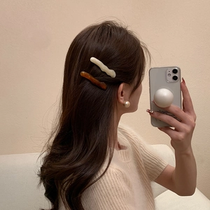 Détail de barrettes en résine crème et ambre avec une grande boucle d'oreille perle