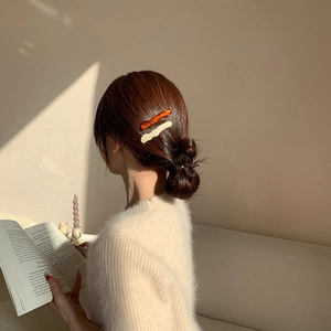 Détail de pinces à cheveux ondulées en acrylique ambre et crème sur un chignon