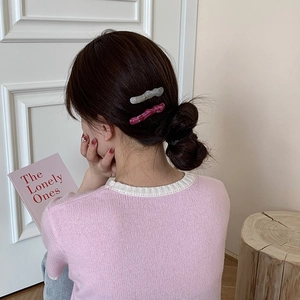 Détail de pinces à cheveux ondulées en acrylique gris et rose sur un modèle
