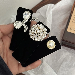 Three-piece set of velvet pearl and rhinestone hair clips on a black card