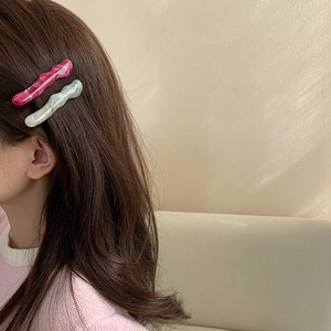 Gros plan de barrettes à vagues irrégulières en acrylique rose et blanc nacré