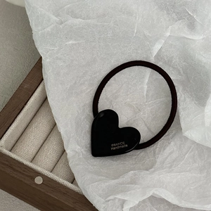 Dettaglio dell'elastico per capelli nero con cuore in acetato e logo dorato France Handmade