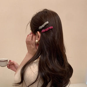 Barrettes à cheveux en acrylique à motif marbré portées sur cheveux bruns ondulés
