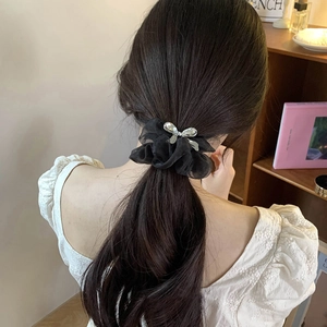 Elegant black organza hair scrunchie with silver rhinestone bow on model ponytail