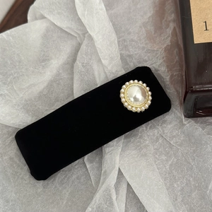 Detail of vintage black velvet hair clip with a large pearl center and gold metal base