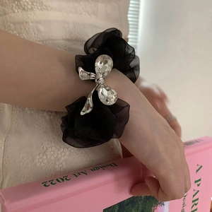 Detail of a black organza scrunchie featuring a silver bow and clear teardrop crystals