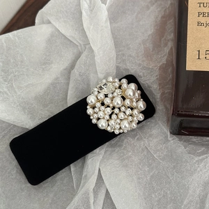 Close-up of black velvet hair clip featuring intricate pearl and rhinestone circular decor