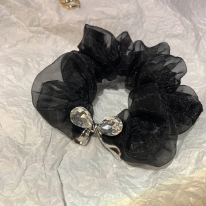 Close-up of black organza scrunchie with a silver rhinestone bow detail and subtle shimmer