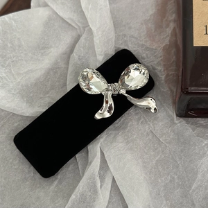 Macro detail of black velvet hair clip featuring a silver bow and teardrop crystal