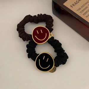Detail van fluwelen haarelastiekjes met gouden smiley bedeltjes en metalen labels