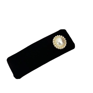 Elegant round pearl brooch with gold metal base and rhinestone detail on black velvet