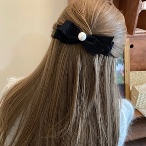 Pink tweed bow hair clip with a large pearl detail worn on long hair for women