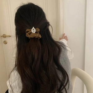 Brown satin scrunchie with embossed flower pearl charm shown on long dark hair