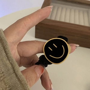 Detail van een hoog-elastische fluwelen haarelastiek met gouden smiley-embleem