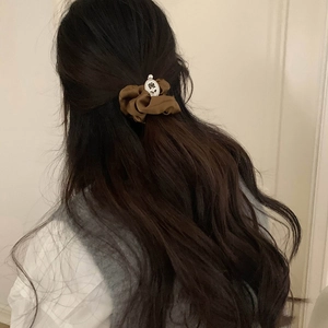 Detail view of dark coffee satin hair tie with vintage floral embossed metal charm