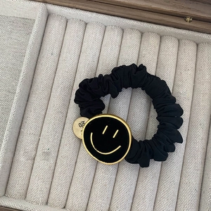 Detail van de zwarte fluwelen scrunchie met gouden smiley en gegraveerde Hope hanger