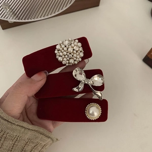 Close-up of red velvet hair clips with pearls, rhinestones and elegant gold details