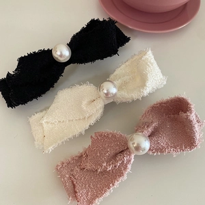 Pink and black tweed bow hair clips with large white pearls on a soft pink tray