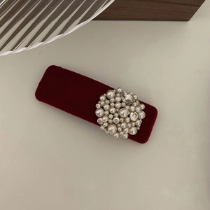 Close-up of a burgundy velvet hair clip with elegant pearl and rhinestone decorations