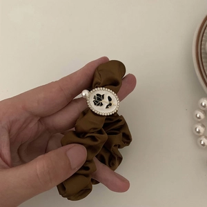 Detail of silk coffee scrunchie featuring black rose motif and pearl accents