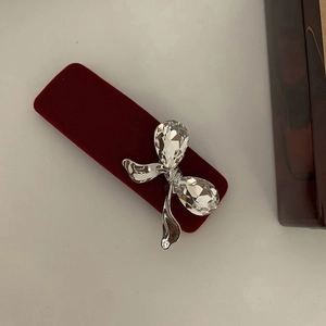 Detailed view of red velvet hair clip with silver bow and teardrop crystal embellishments