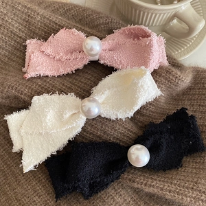 Detail showing tweed texture bow hair clips with faux pearls in pink, white, and black colors