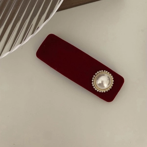 Close-up of a burgundy velvet hair clip with a pearl and gold bead floral detail