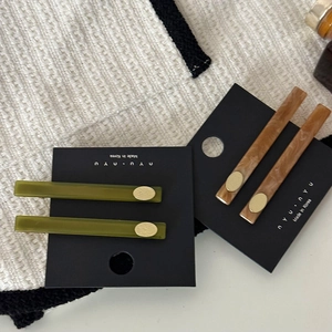 Barrettes en acétate marbré vert et marron avec accents métalliques dorés sur carte
