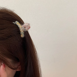 Dettaglio di una mini clip per capelli in maglia colorata indossata per styling laterale