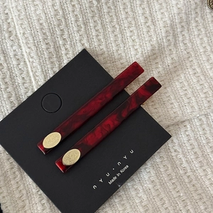Détail macro de barrettes à texture marbre rouge foncé avec plaques dorées ovales