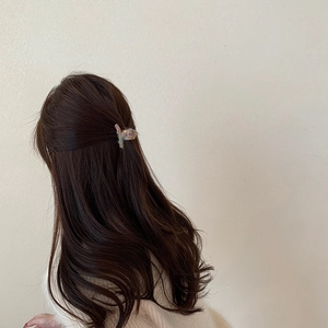 Dettaglio di una mini clip per capelli in maglia colorata in una mezza acconciatura