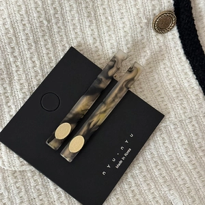 Gros plan de barrettes à cheveux en acétate marbré avec plaques dorées sur du tweed