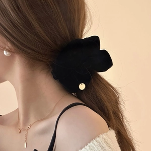 Elegante elastico in velluto nero con ciondolo in metallo dorato su uno chignon