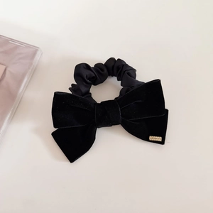 Detailed macro of black velvet bow hair tie with gold metal label engraved with LOVEDAYS