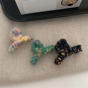 Dettaglio della trama delle mini mollette per capelli in lana colorata beige verde e nera