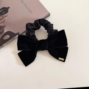 French vintage black velvet bow hair tie with a gold metal tag on white background