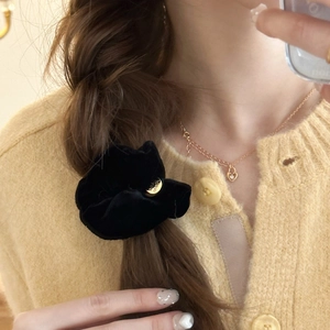 Dettaglio di un elastico per capelli in velluto nero con logo in metallo dorato