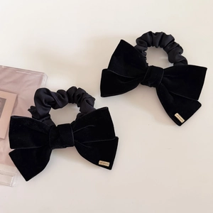 Set of two black velvet bow hair ties featuring a small gold-toned metal tag embellishment
